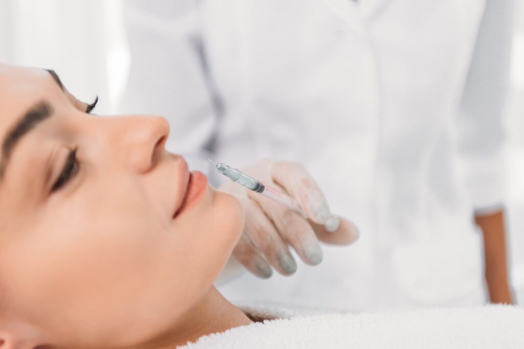 A serene beauty session captures a cosmetologist in sterile gloves administering a delicate Hyaluronic Acid Dermal Fillers treatment to a relaxed patient, highlighting the precision of cosmetic care.